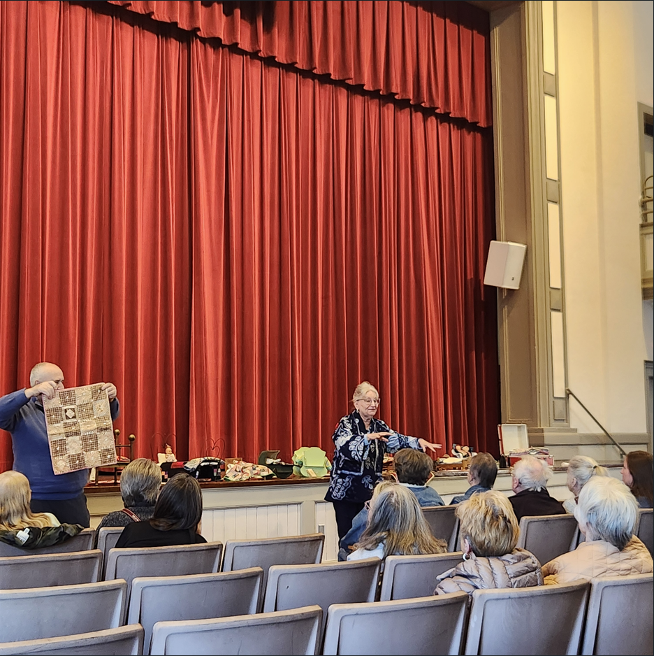Presenters showing off a quilt infront of a crowd